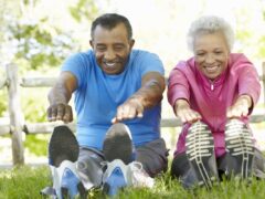 older couple stretching before exercise in a park