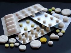 Sealed tablets packs and scattered pills on black surface