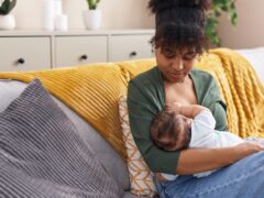 Mother and son sitting on sofa breastfeeding at home